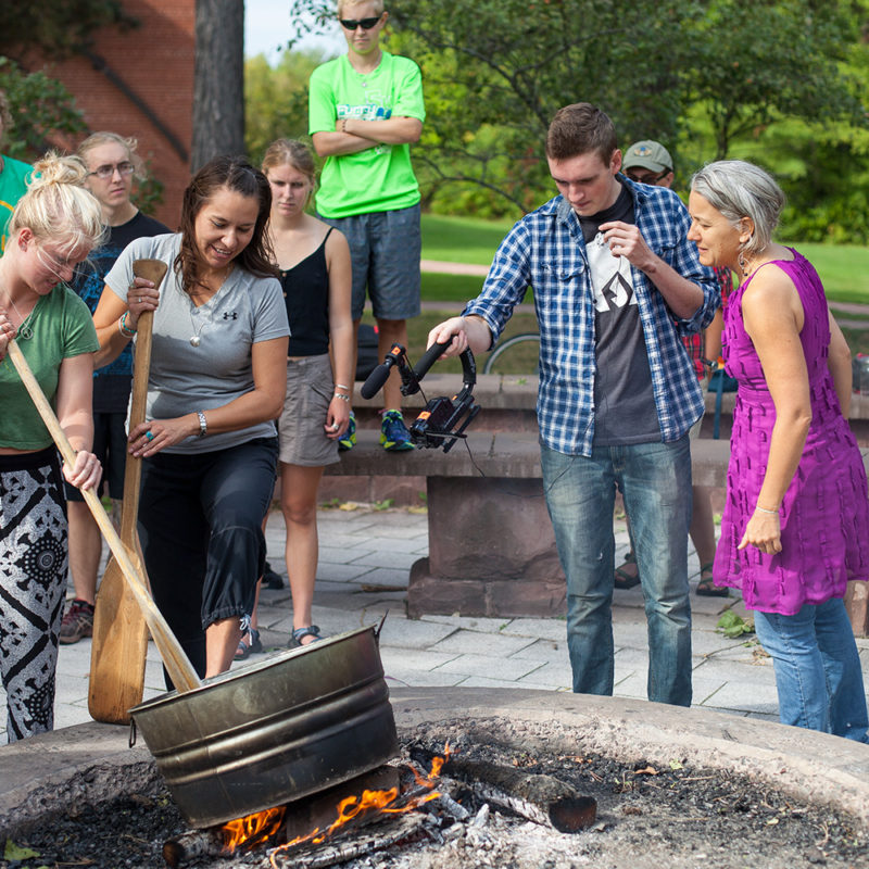 Students parching their hand-harvested wild rice over a campfire at the campus fire-ring.